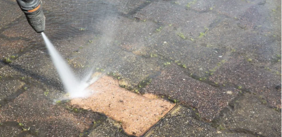 Commercial storefront being pressure washed, clear glass windows, urban setting, technician in uniform, water mist in air, early morning light, 3:2 aspect ratio