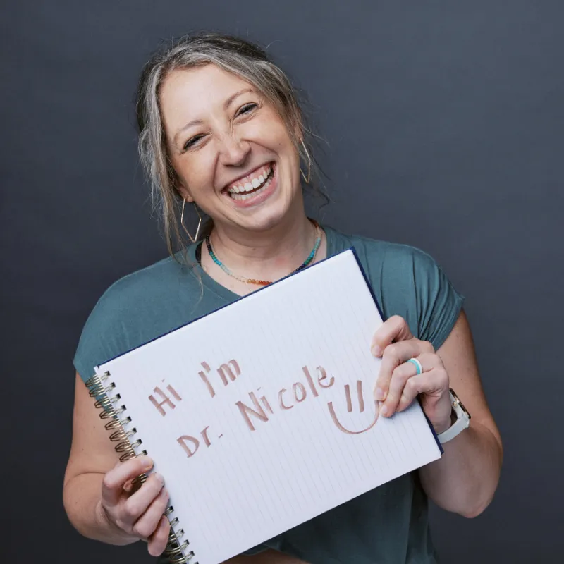Warm portrait of Dr. Nicole smiling welcomingly in a bright, modern studio space