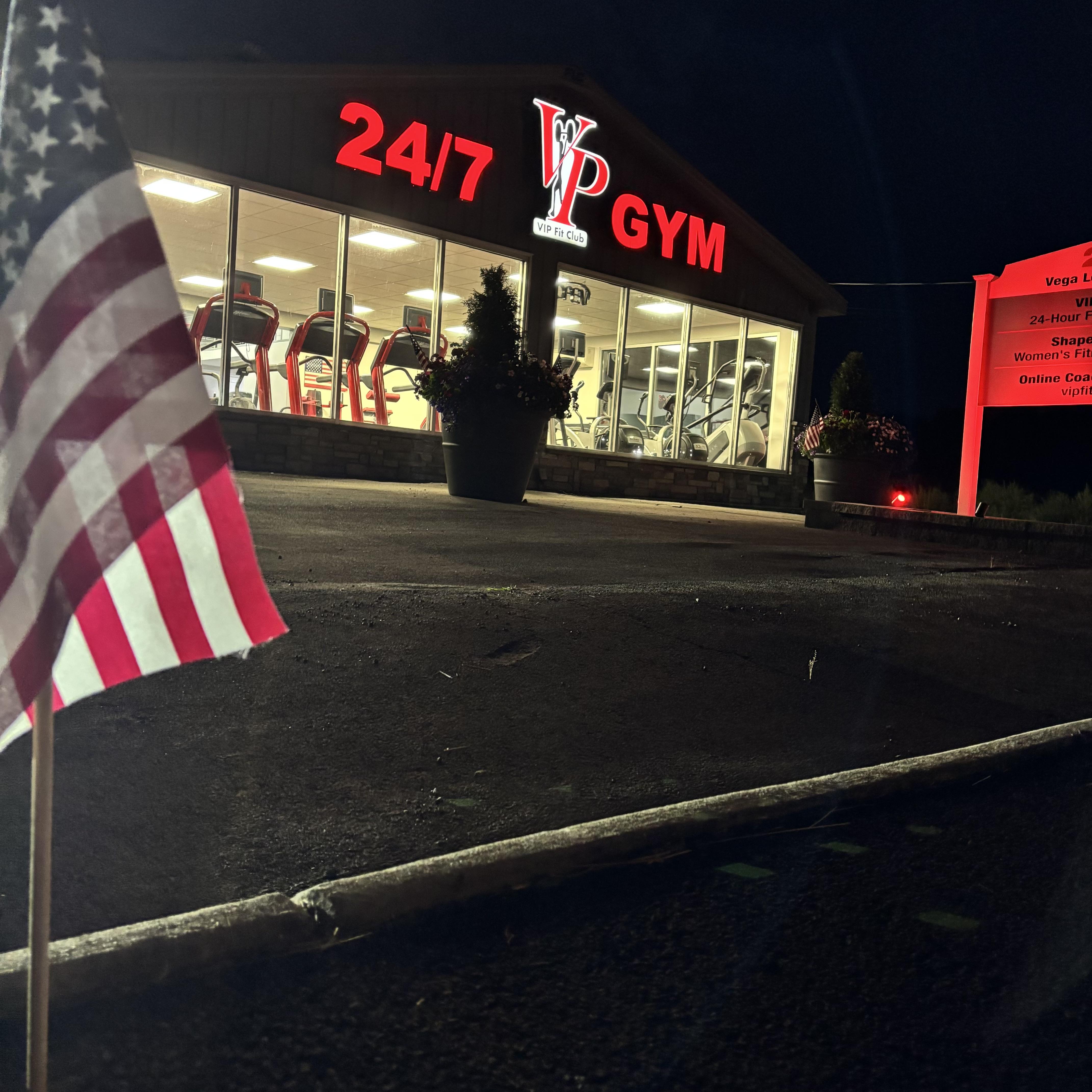 Receptionist at a modern wellness spa, smiling warmly while answering a phone call at a sleek wooden desk. The background features lush indoor plants and soft, natural lighting, creating a welcoming and professional atmosphere.