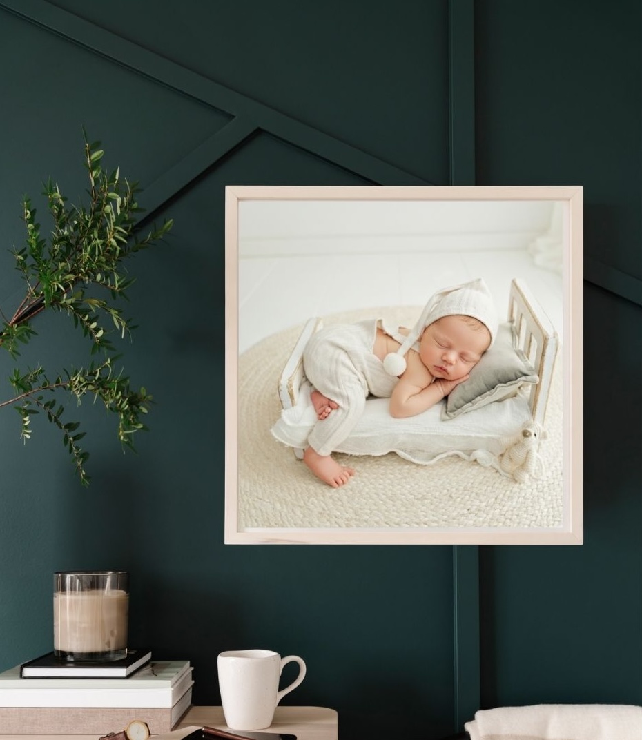 Babyjunge beim Babyshooting Hamburg posiert in Bauchlage auf eine weißen Bettchen aus Echtholz in weißem Babystrampler und Zipfelmütze dekotiert mit weißem Teddybär