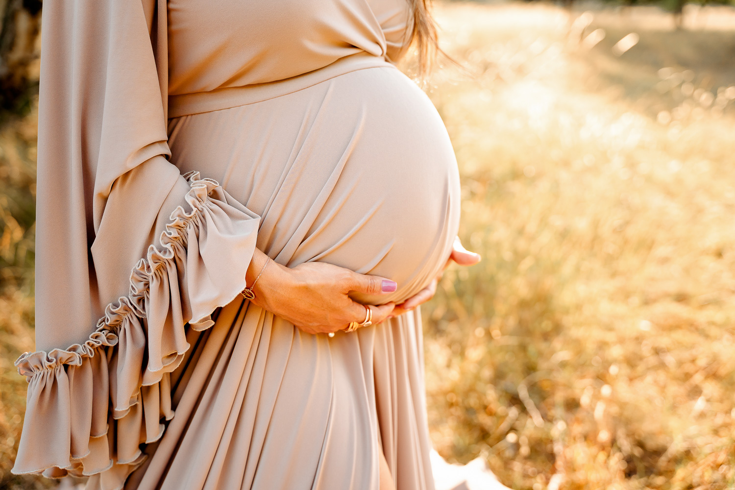 Babybauch Detailfoto mit warmen Sonnenstrahlen auf einer Wiese