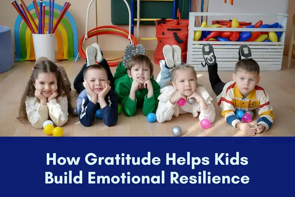 5 happy-looking children stretched out on their tummies with their chins resting on their hands