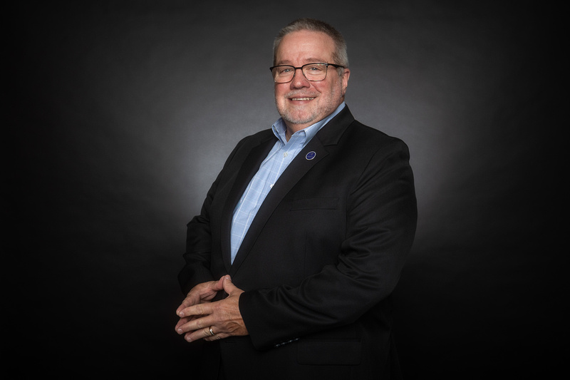 Professional portrait of Ray Riddle in a speaking environment