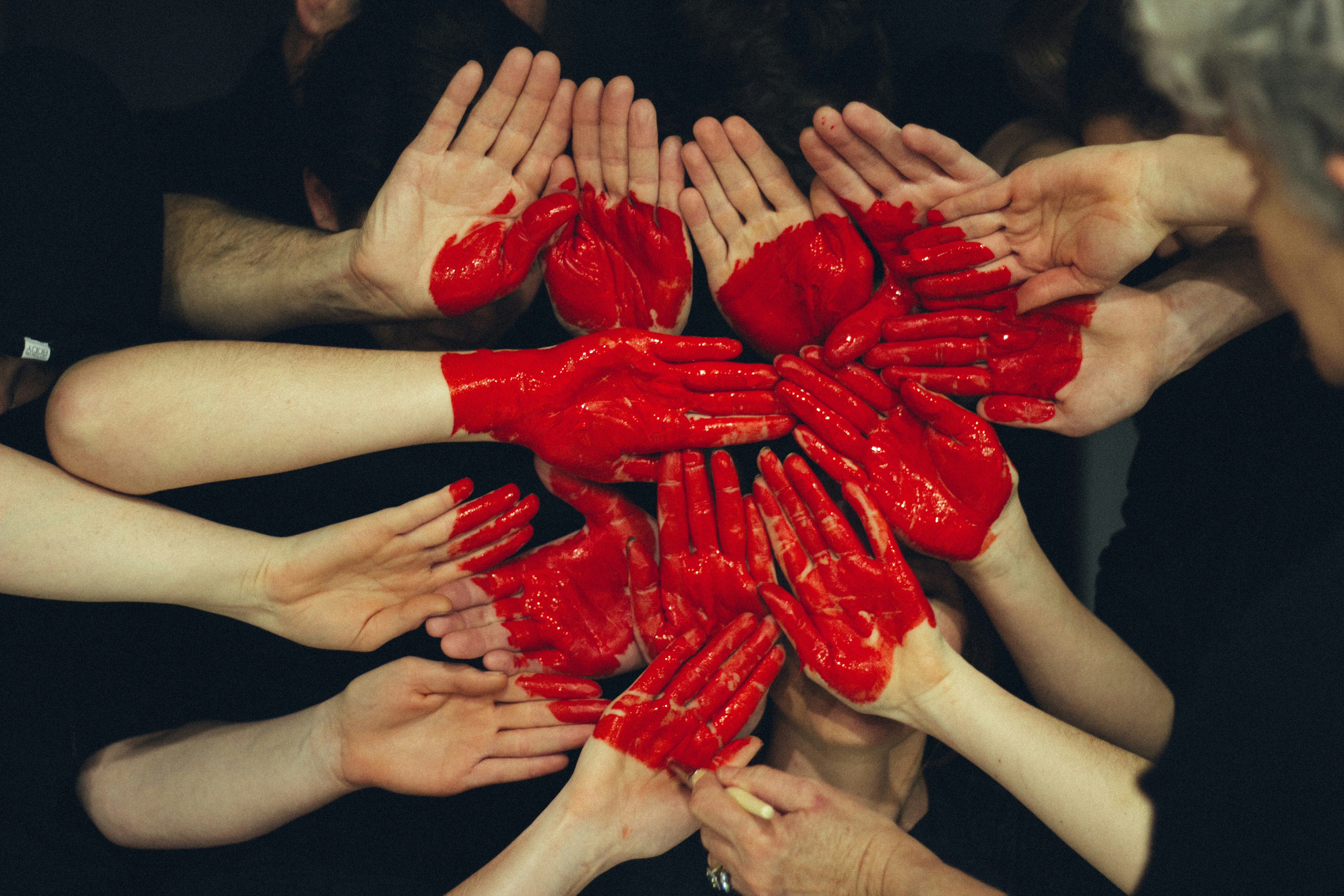 Women coming together to create a painted heart with their hands.