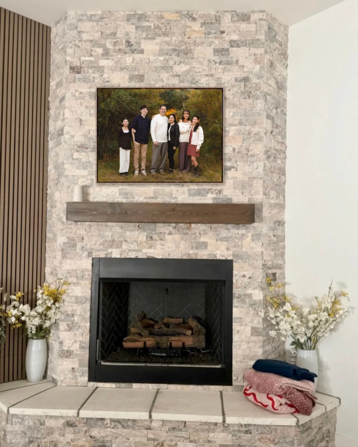 Framed family portrait hanging above a stone fireplace in a Gilbert home, heirloom wall art by Andria May Photography