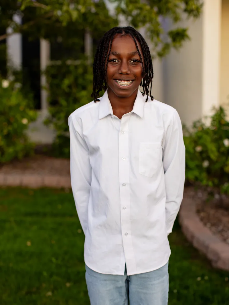 Young boy in a white button up shirt standing outdoors during a children's portrait session with Andria May Photography in Gilbert, Arizona