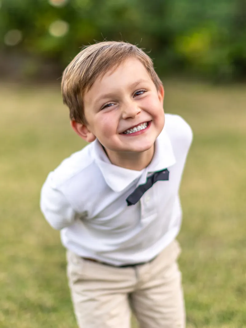 Young boy in a bow tie laughing during an outdoor children's portrait session with Andria May Photography in Gilbert, Arizon