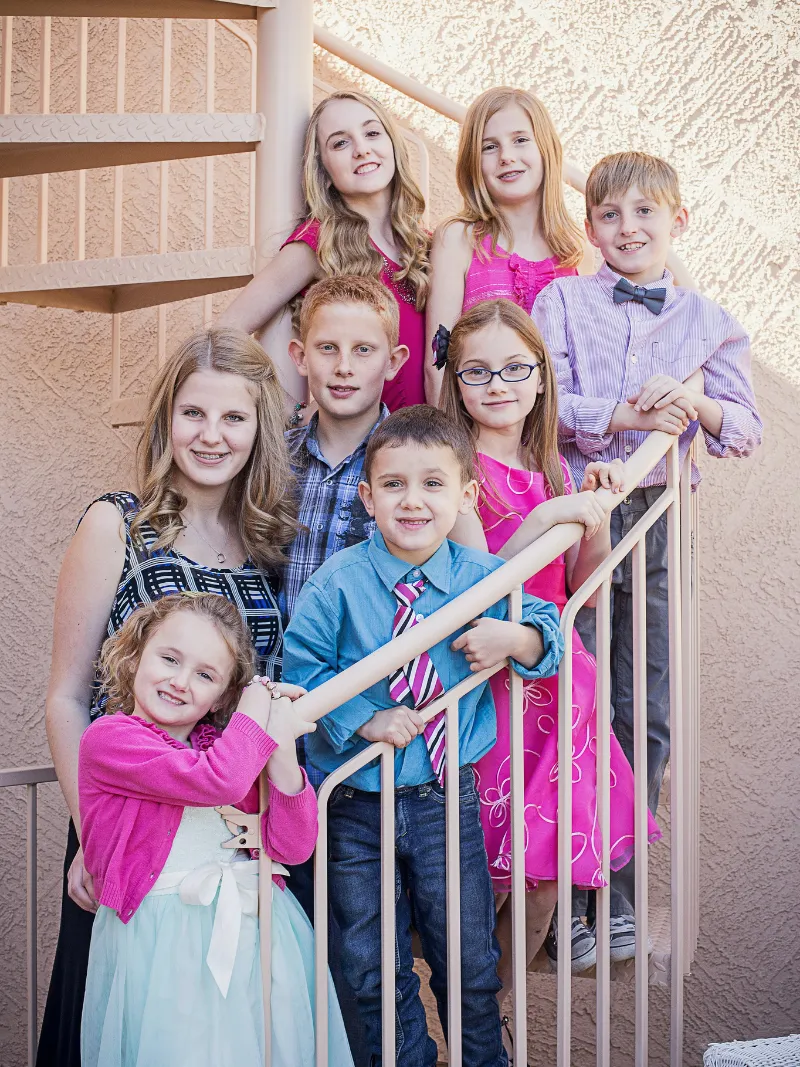 Seven siblings posing together on a staircase during a family portrait session with Andria May Photography in Gilbert, Arizona