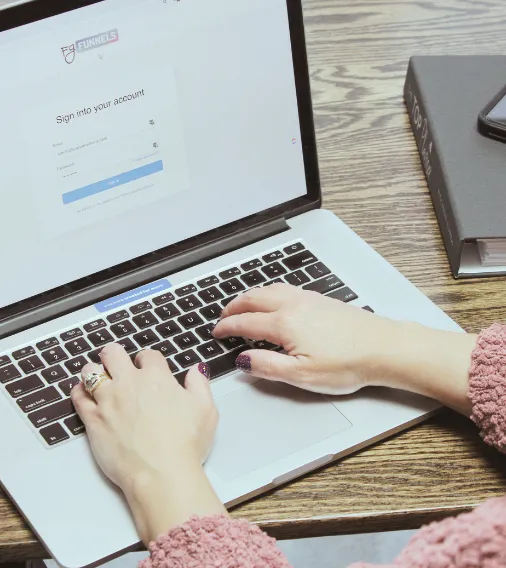 Close-up of a woman's hands typing on a laptop, logging into FG Funnels, symbolizing the transition to entrepreneurship and virtual assistance.