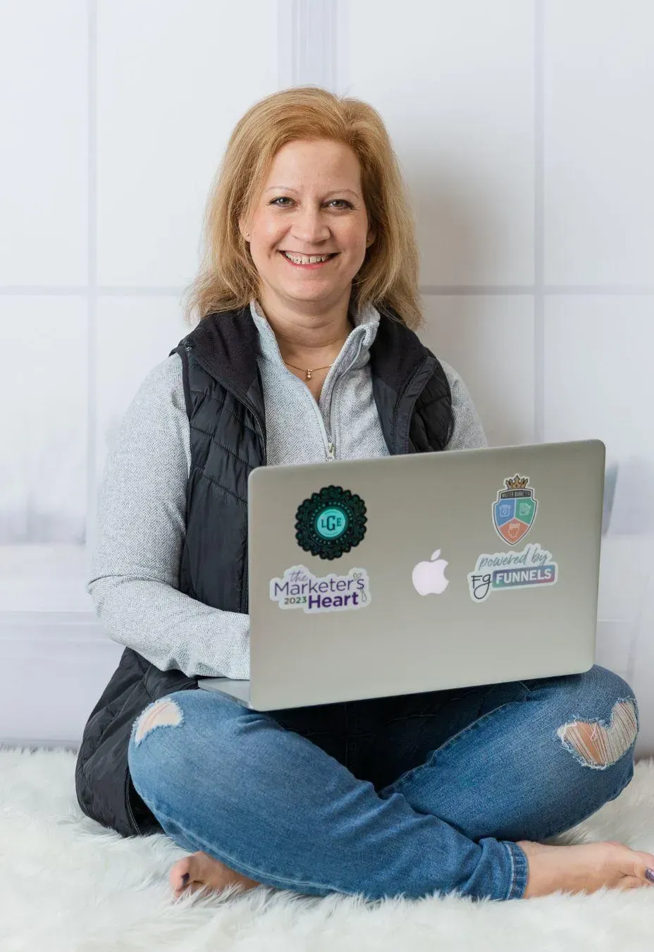 woman sitting on a rug with her laptop smiling