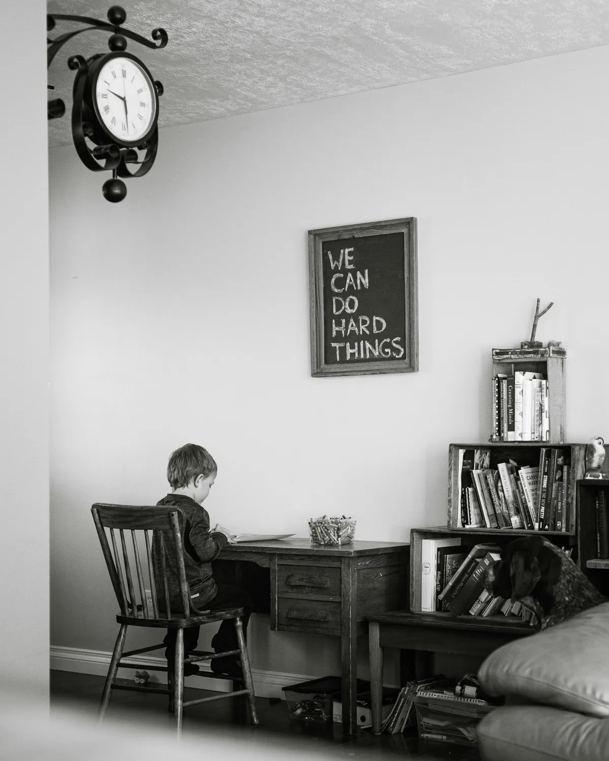 child sitting at a desk, organized space, sign on the wall says "we can do hard things"