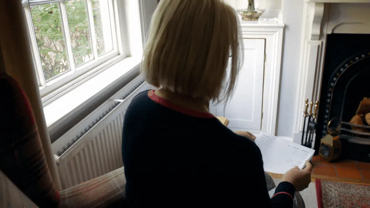 Woman opening past due bills — relief after selling her home for a cash offer.