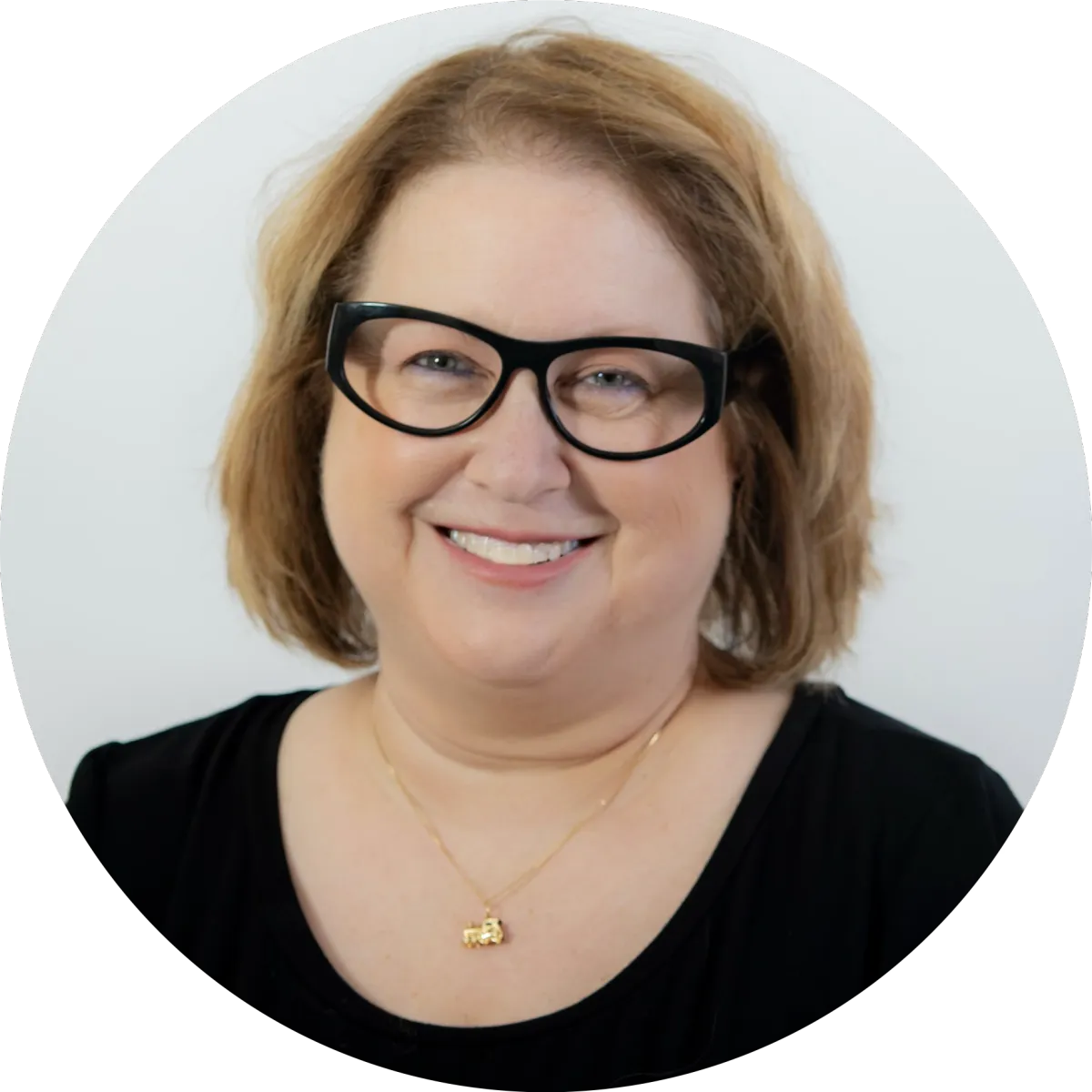 Linda Gutin headshot, grinning, black top and eyeglasses