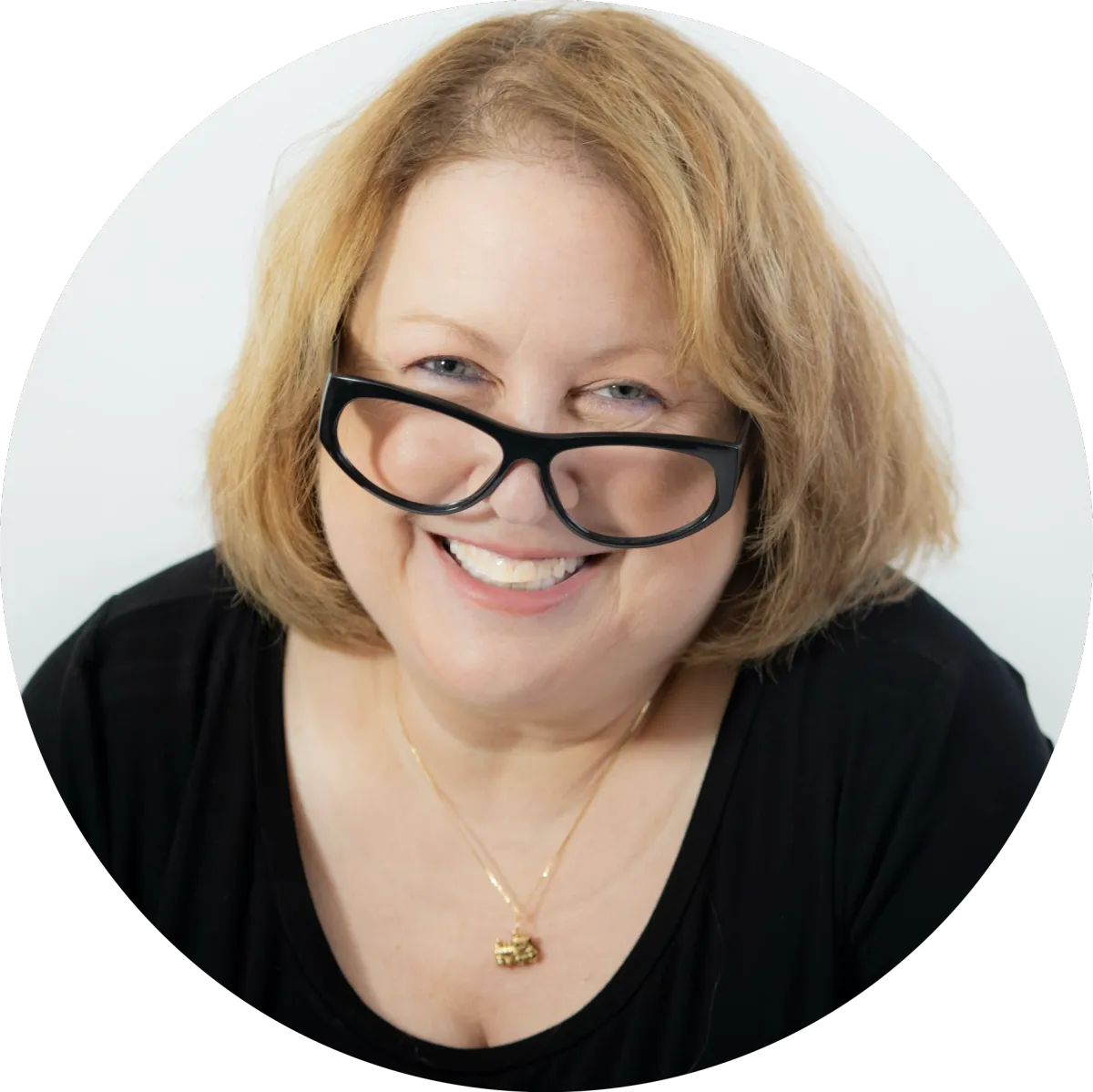 Linda Gutin Headshot, looking over her glasses at you and smiling