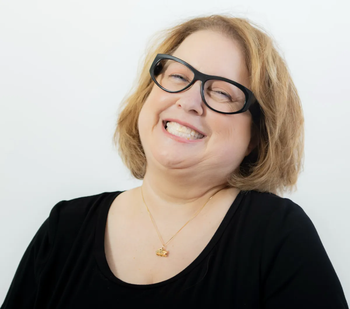 Linda Gutin headshot, grinning, black top and eyeglasses