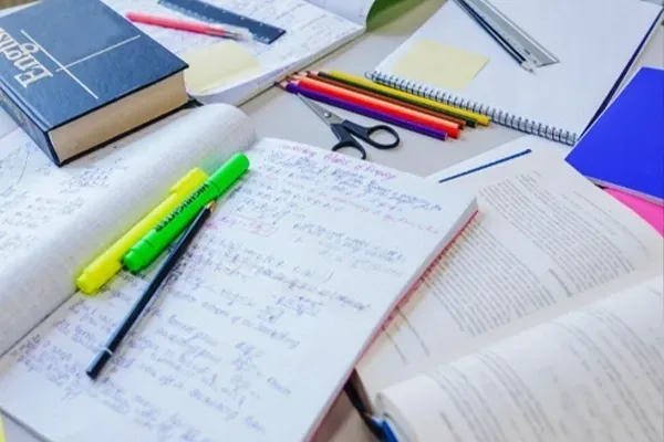 notebooks, books, pens and markers sitting on a table