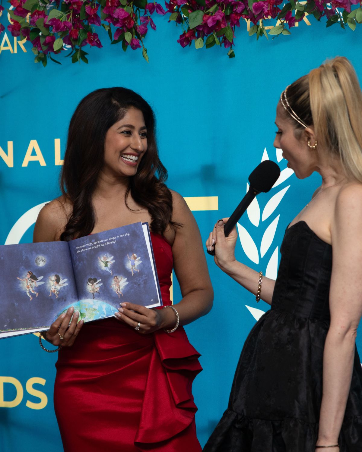 An author holding her book open to camera while being interviewed at an International Impact Book Awards event.