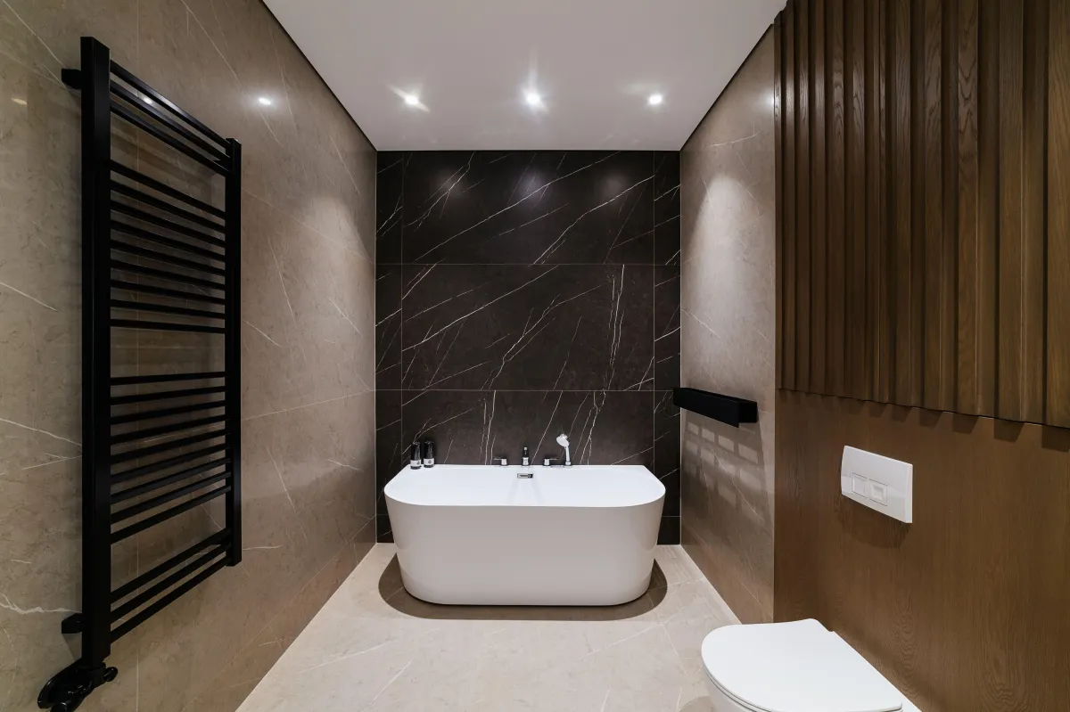 "Modern bathroom with freestanding tub, black accent wall, and wood panel detailing — luxury renovation by B&Y Reno Corp."