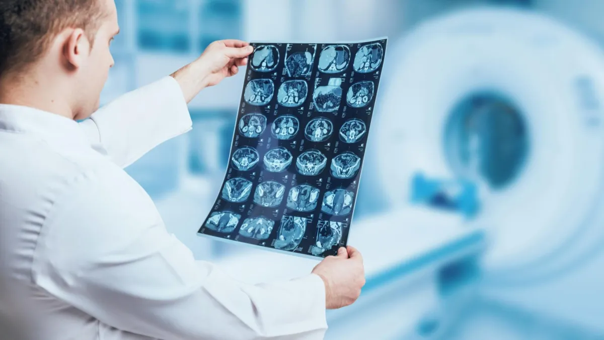 A healthcare worker is carefully studying a medical image, holding it up to the light.