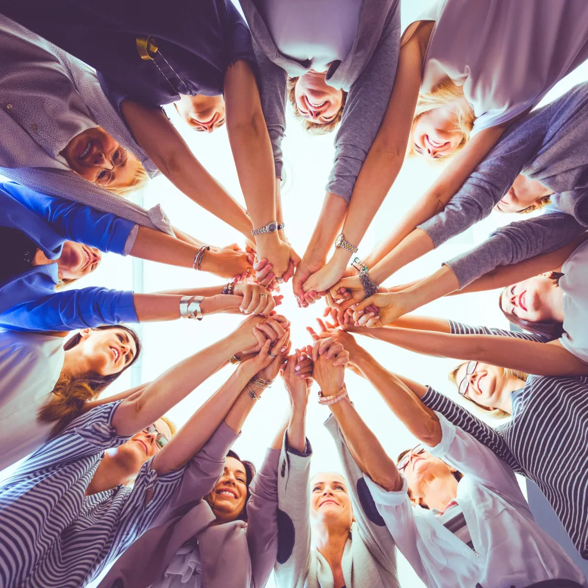 A cohesive team of healthcare professionals is united in their commitment to patient care, symbolized by their hands joined in a circle.