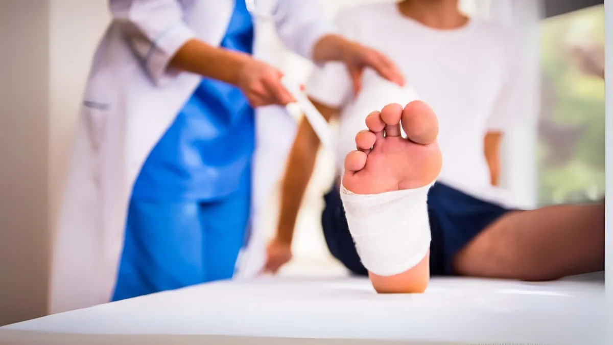 A doctor is carefully examining a patient's foot, which is wrapped in a bandage.