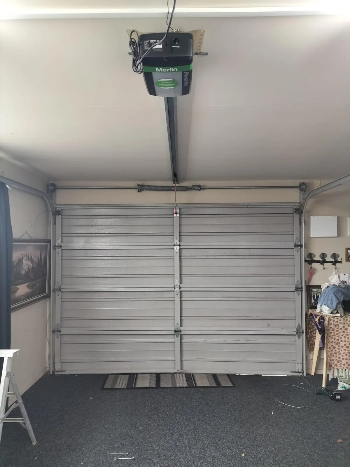 Interior of a garage featuring an automated garage door opener installed on the ceiling with a roller door.