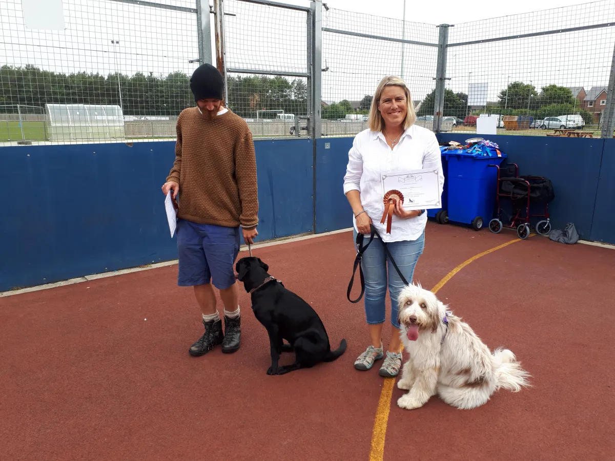 2 dogs graduating silver lifeskills with owners displaying silver certificate