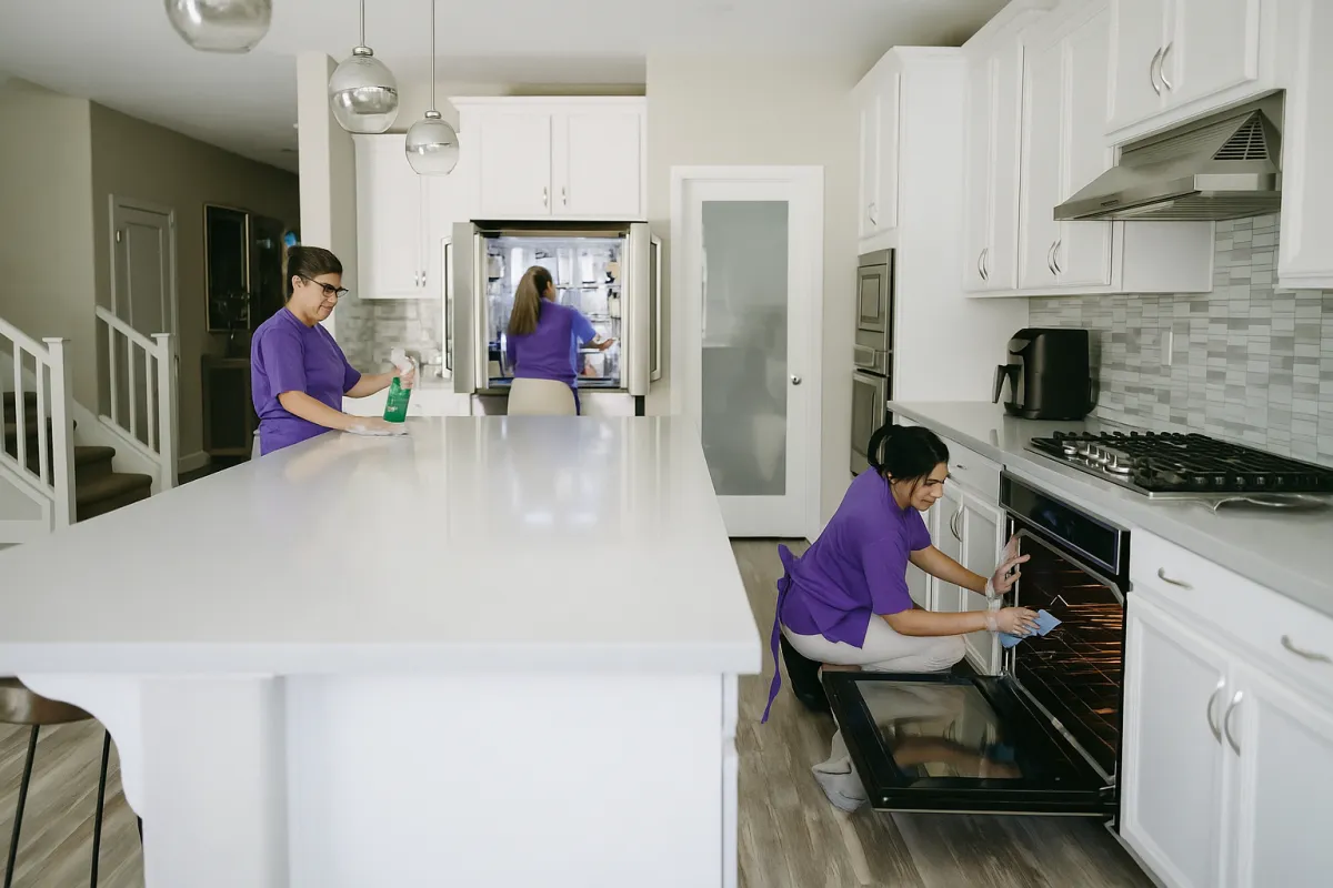 A close-up of gloved hands scrubbing a kitchen countertop in a high-rise NYC apartment, with cleaning supplies neatly arranged nearby. The countertop gleams under bright lighting, emphasizing the attention to detail and cleanliness.