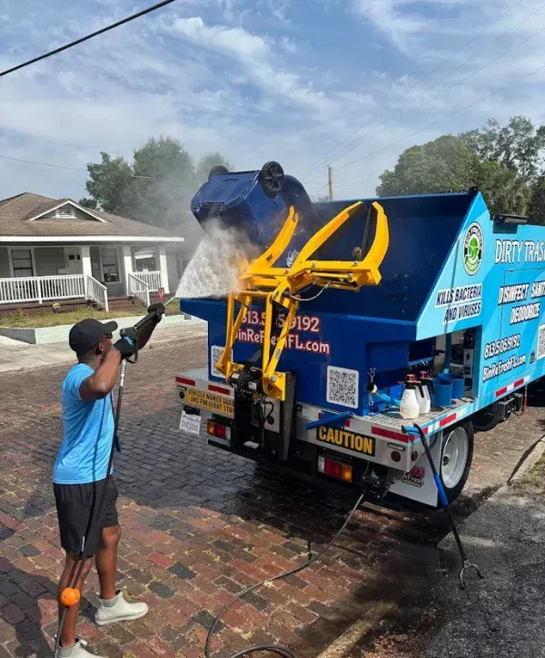 Bin Refresh owner power washing a trash bin using truck-mounted cleaning system