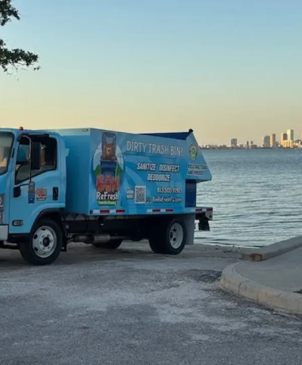 Bin Refresh trash bin cleaning truck parked by the waterfront with city skyline in background 
