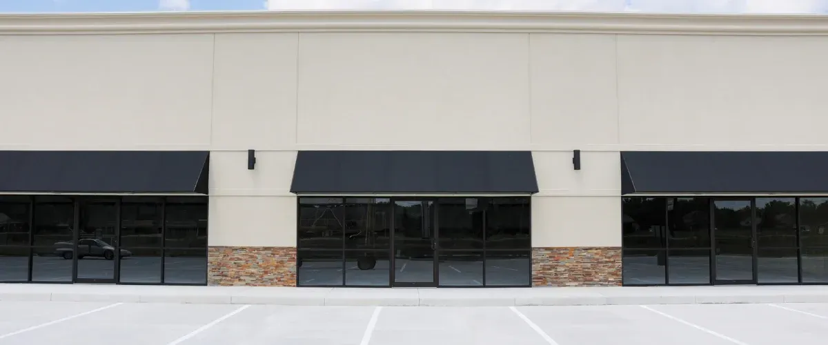Modern commercial building with glass windows and black awnings over entrances