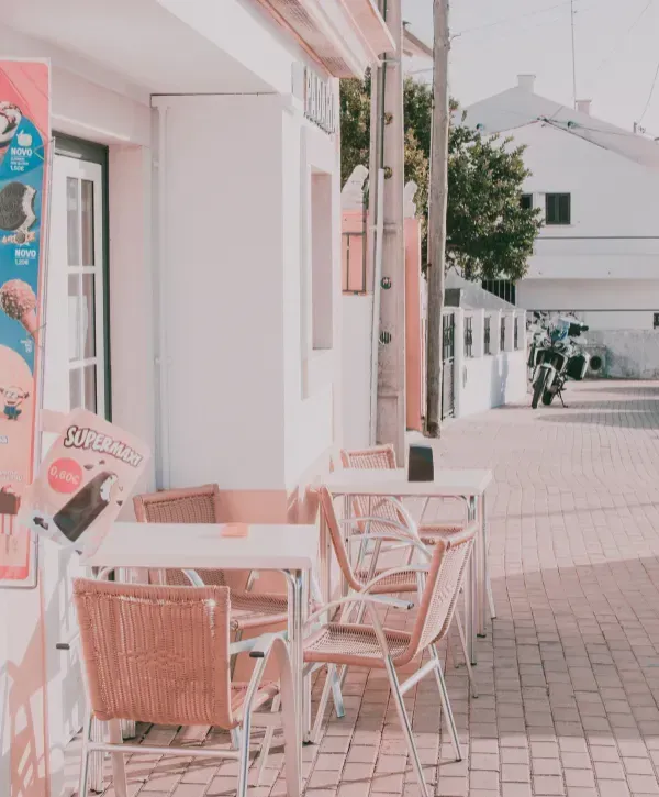 Outdoor café seating area with wicker chairs and tables along a sunlit walkway