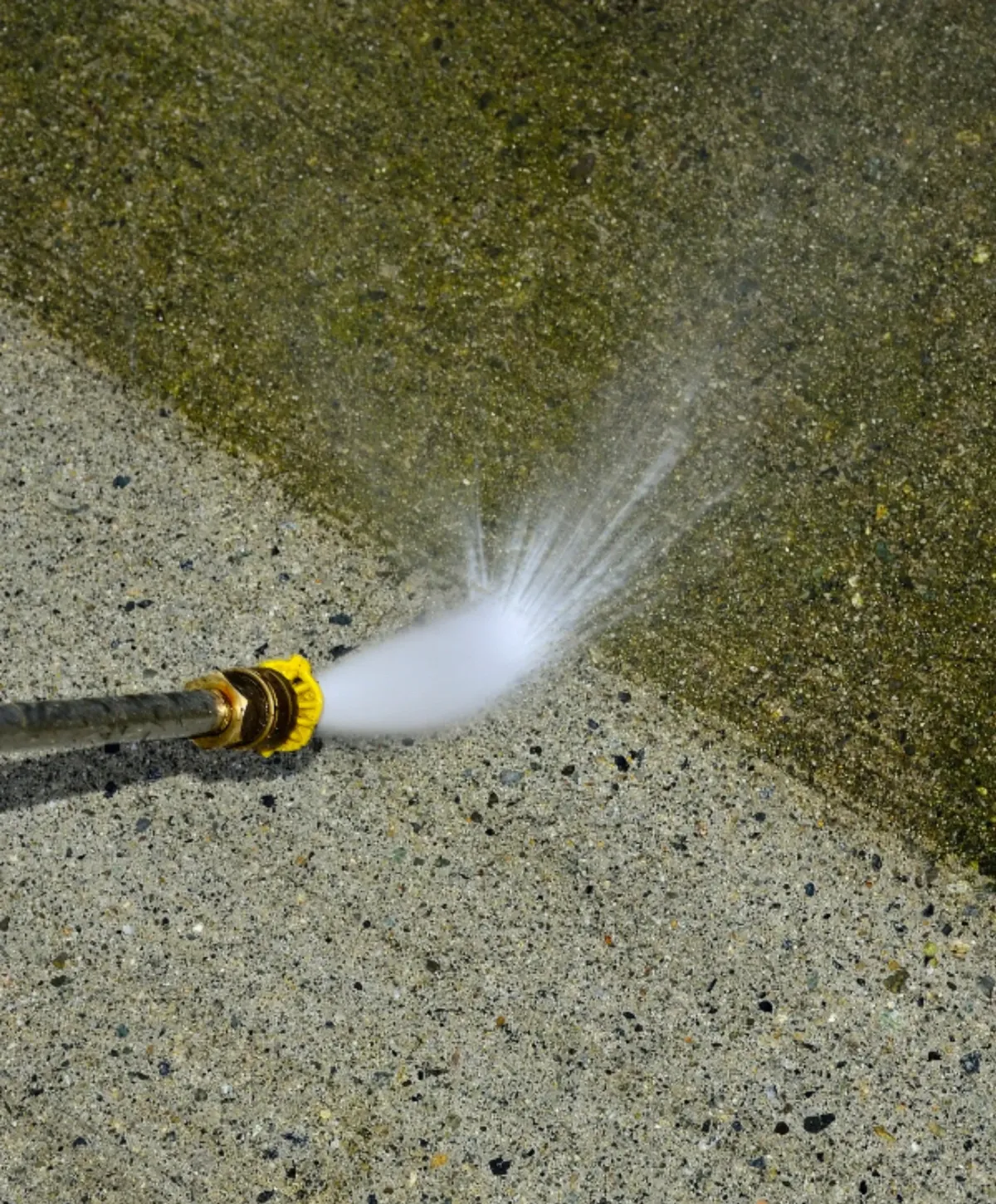 High-pressure washer removing mold and algae from a dirty concrete surface.
