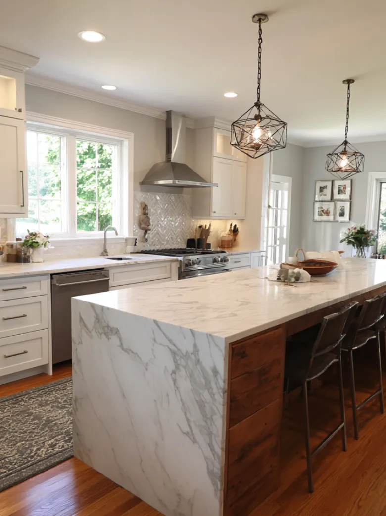Modern kitchen remodel with white shaker cabinets, marble waterfall island, pendant lighting, and stainless steel appliances