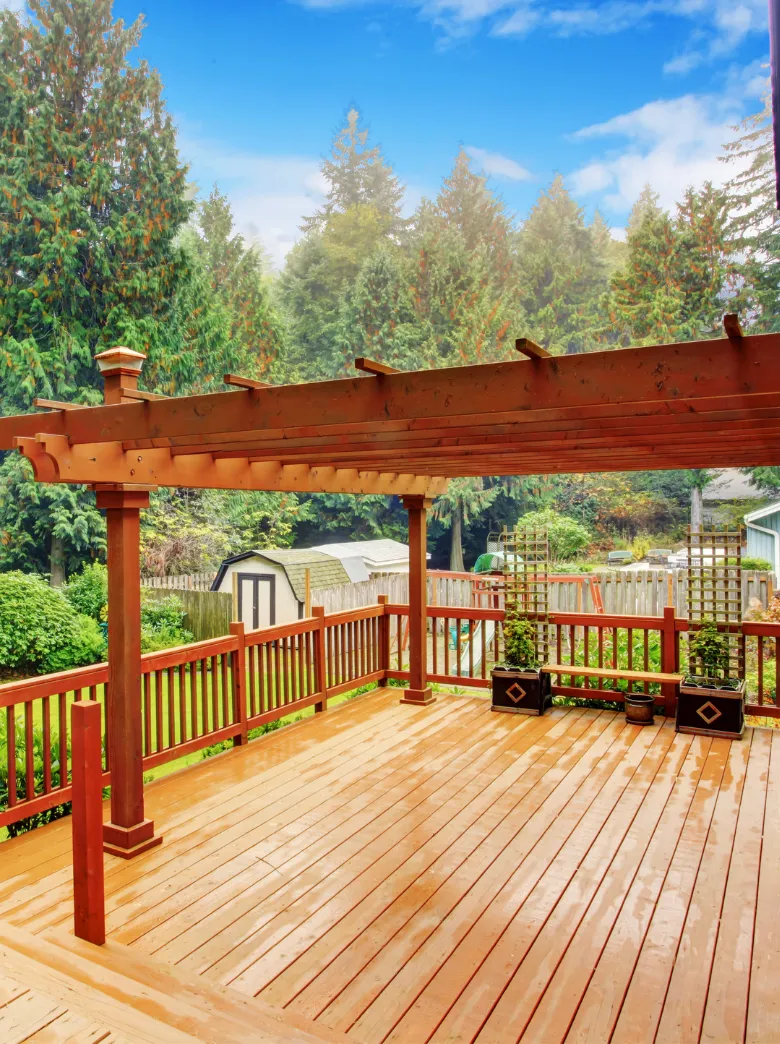 Newly built backyard deck with pergola overlooking landscaped garden and trees