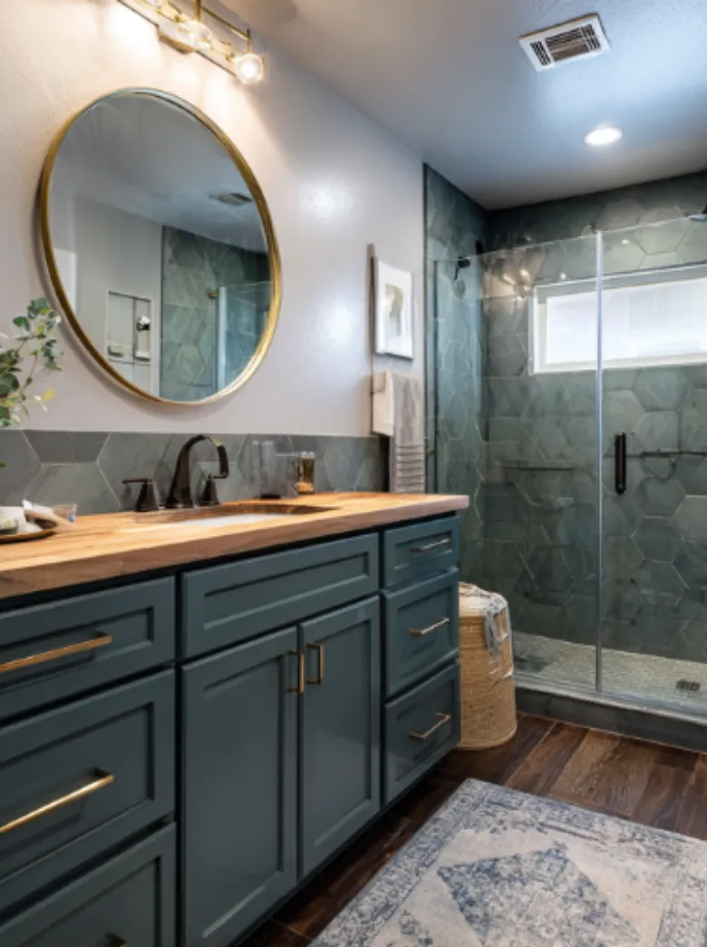 Luxury bathroom renovation featuring navy vanity cabinets, round mirror, wood countertop, and custom tile walk-in shower