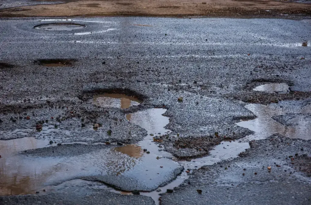 Cracked and heaved asphalt driveway in Maine showing frost heave damage after winter