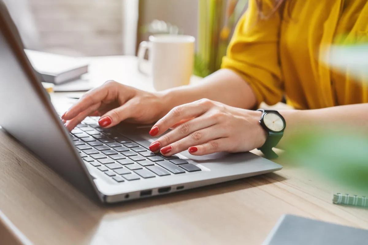 Woman's hands typing on a laptop to represent paid ad management for interior designers