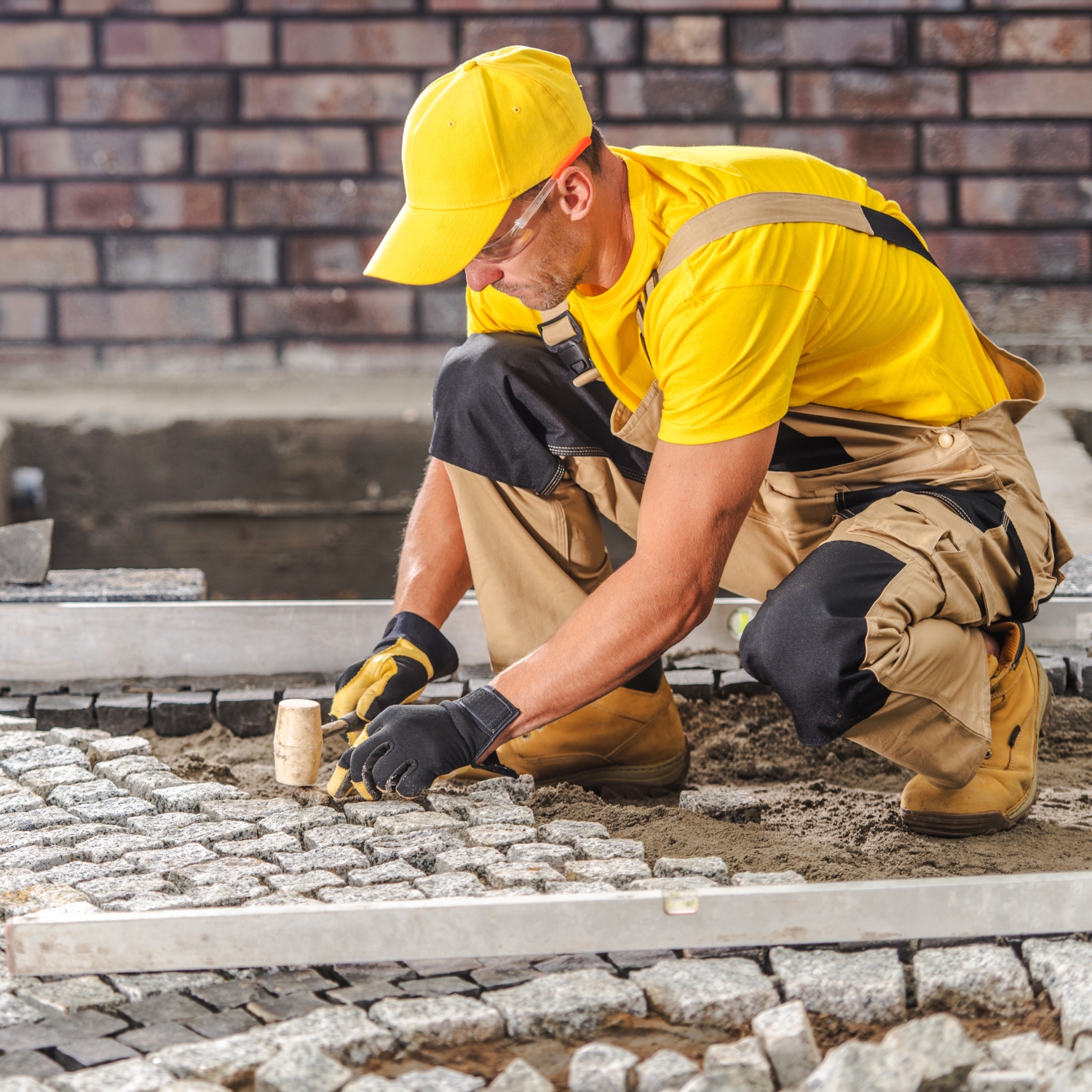Contractor installing stone pavers for outdoor hardscaping project in [CITY]