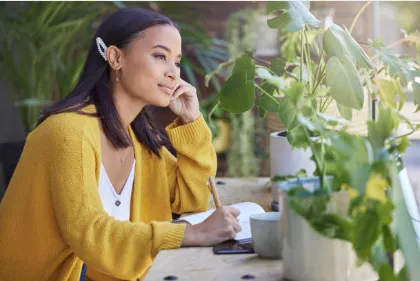 black woman journaling at a desk with plants