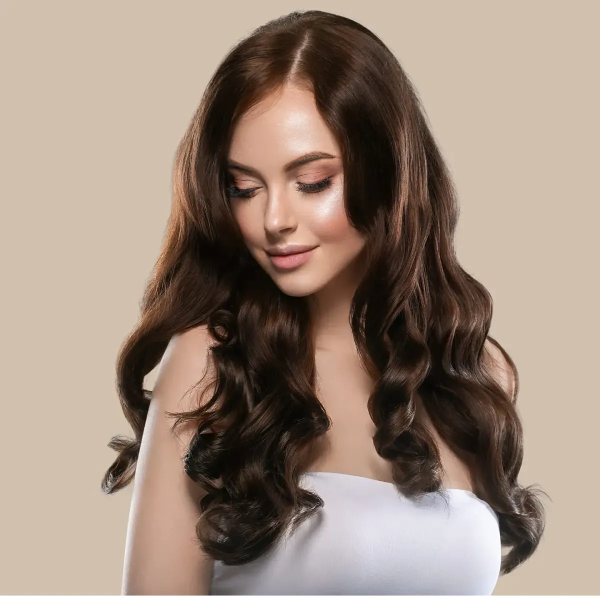 Woman with long, glossy brunette waves styled in soft curls for a luxury salon look
