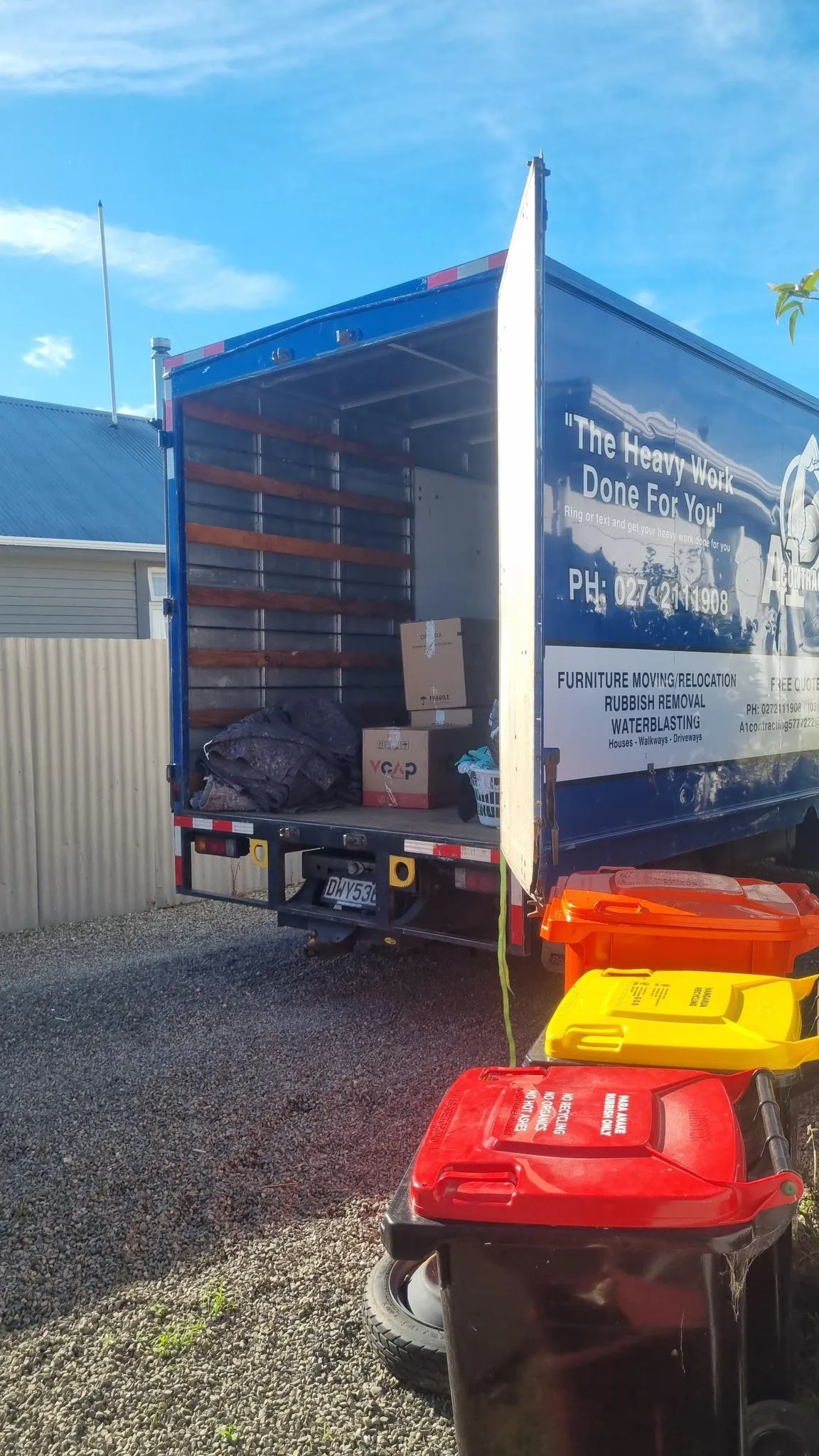 A1 Contracting moving truck parked with household items and recycling bins nearby