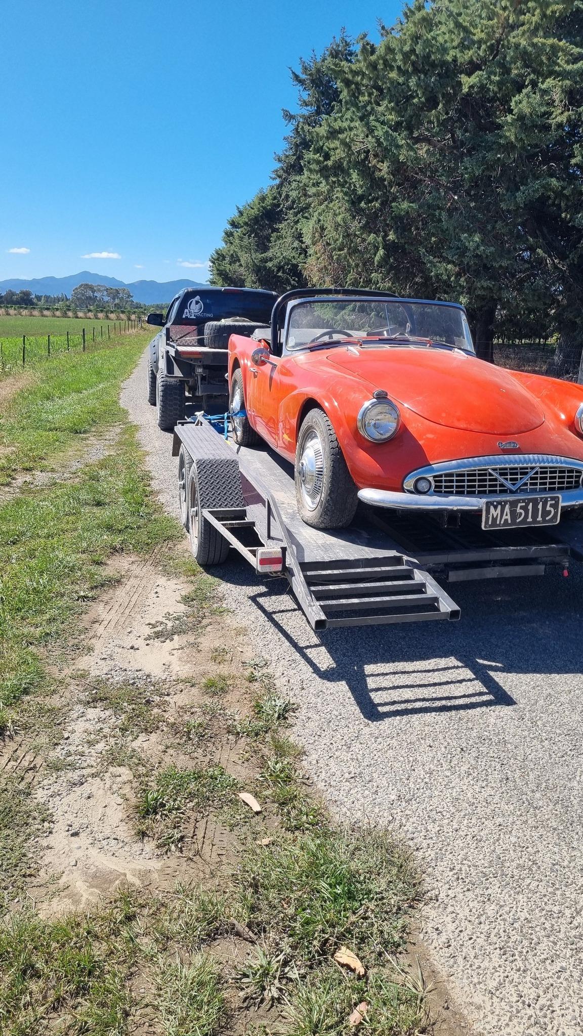 A1 Contracting ute towing a red classic car across rural New Zealand
