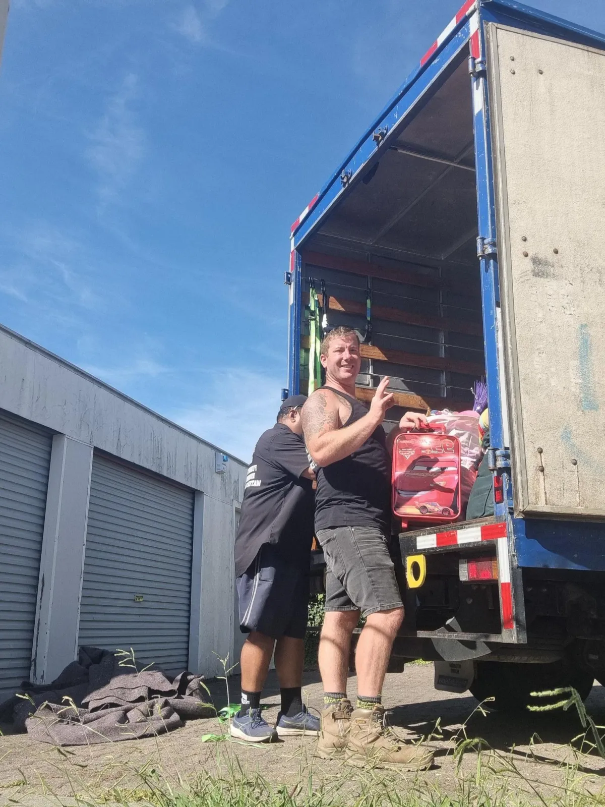 A1 Contracting team unloading household items from a moving truck, with one crew member smiling and giving a thumbs up