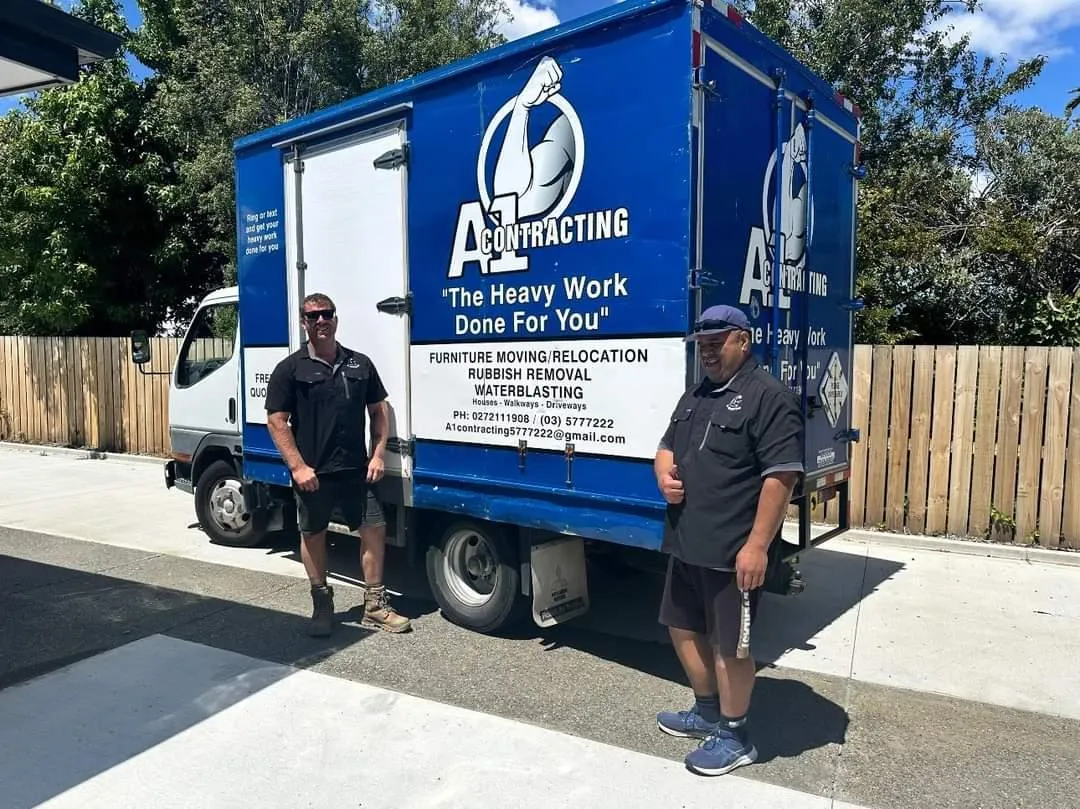 A1 Contracting team standing beside their branded blue moving truck in Blenheim