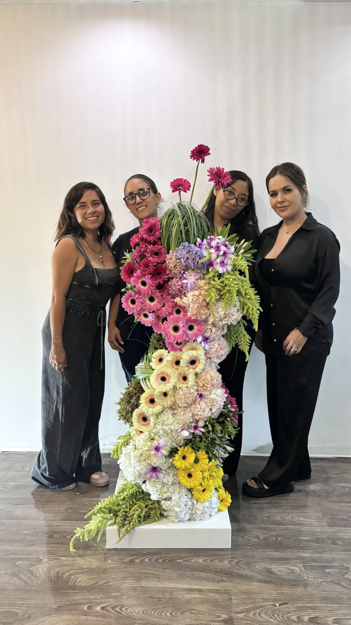 Retrato editorial de instructora mostrando composición floral media luna, fondo crema, énfasis en manos y técnica profesional.