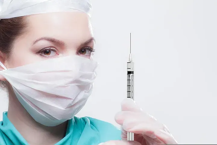 Nurse Wearing a Mask Holding a Syringe Preparing to Give a Weight-Loss Injection