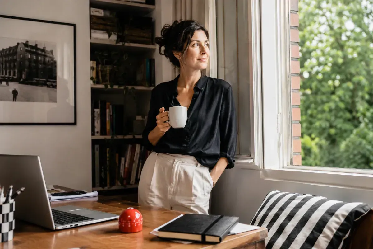 Woman takes a deliberate breathing break beside an open window.