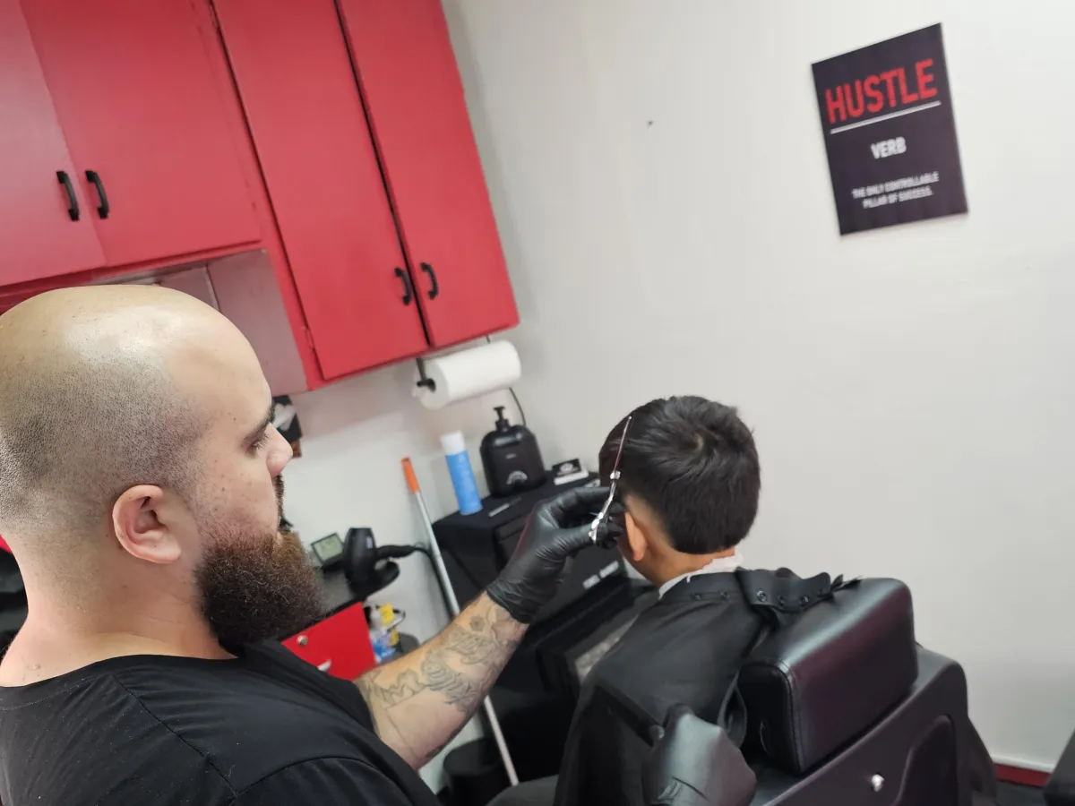 woman cutting the hair of man sitting on barber armchair