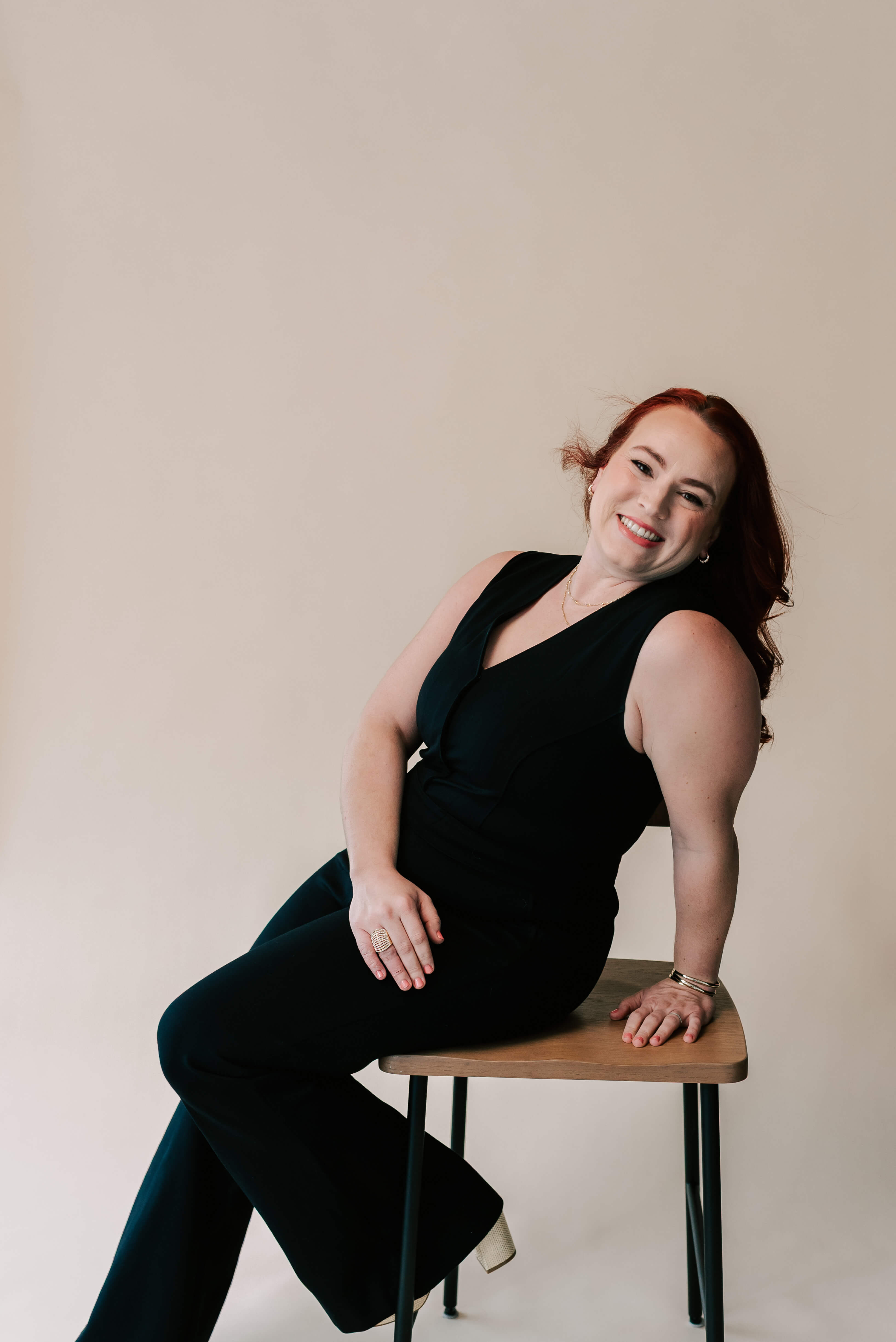 Portrait of Jamie smiling confidently while leaning back on a stool, specializing in bookkeeping for family businesses.